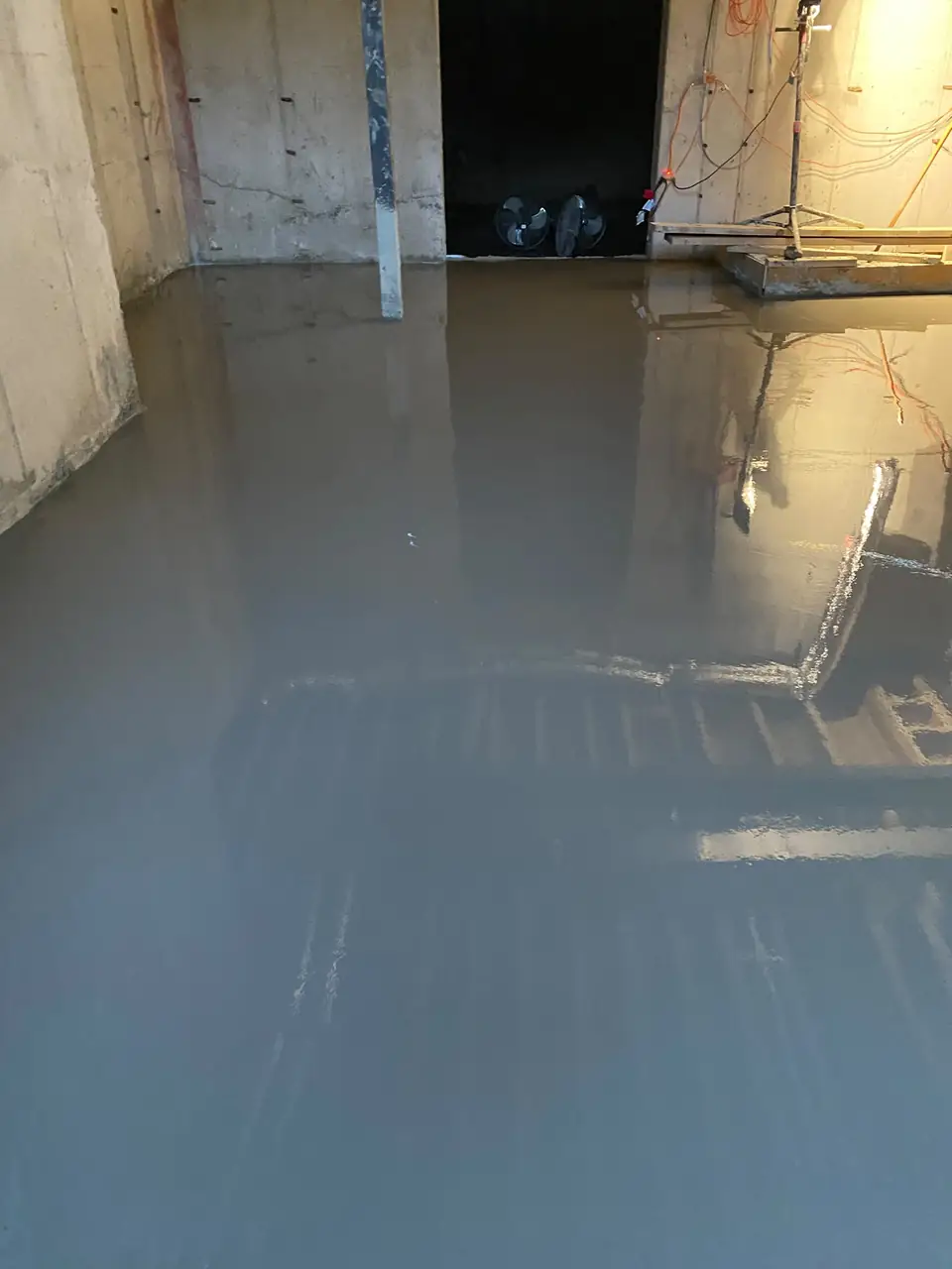 Fresh self-leveling underlayment covering a basement concrete slab from wall to wall