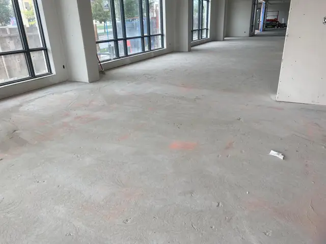 Large open commercial concrete floor with layout marks before grinding and leveling