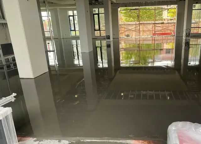 Completed commercial concrete floor leveling with the storefront windows reflected in the surface