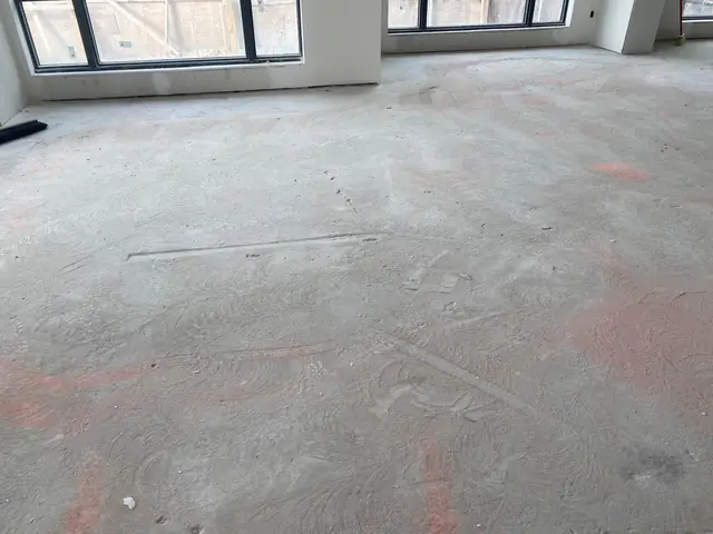Raw condo concrete slab with pink survey markings before self-leveling concrete