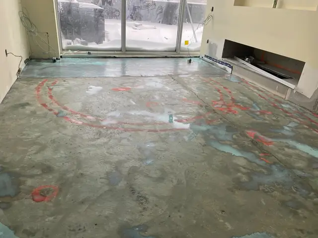 Concrete slab with red spray-paint circles marking high and low spots before floor leveling