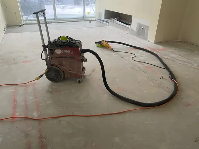 Industrial dust-extraction vacuum on a concrete slab during concrete grinding and floor preparation
