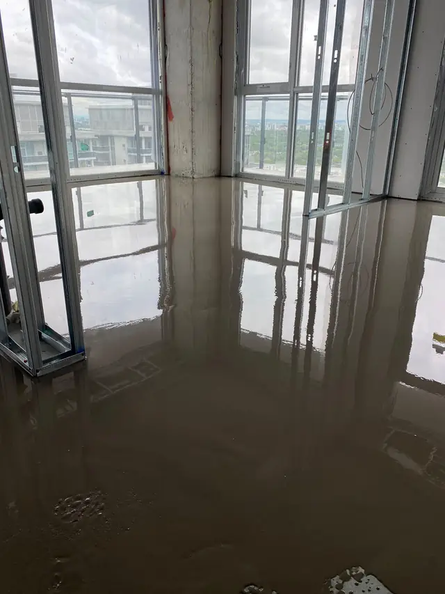 Self-leveling concrete poured in a high-rise condo unit with floor-to-ceiling windows