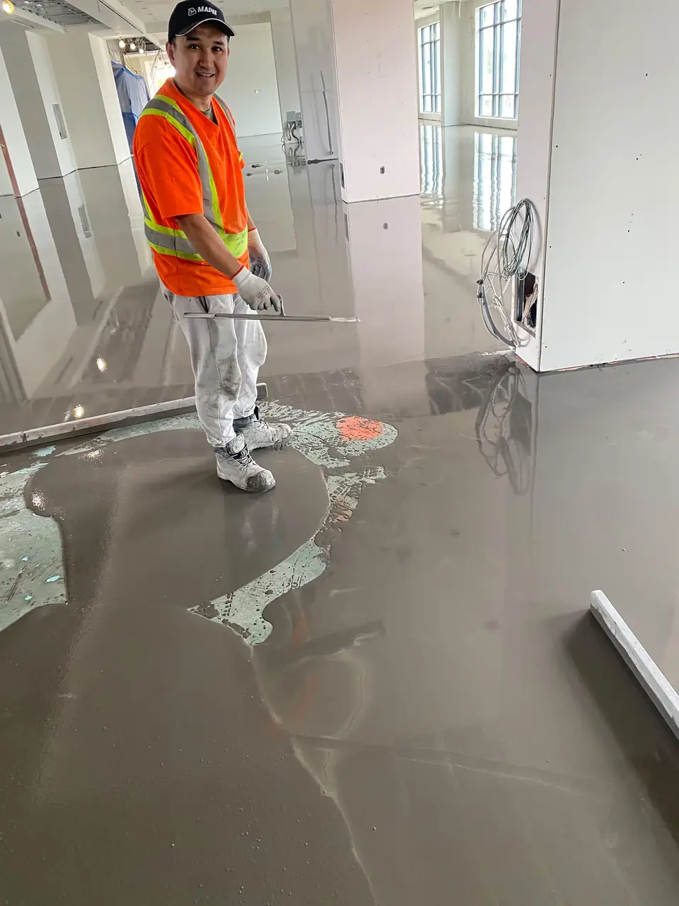 MIR Concrete Floor Leveling installer in a safety vest standing on a fresh self-leveling pour