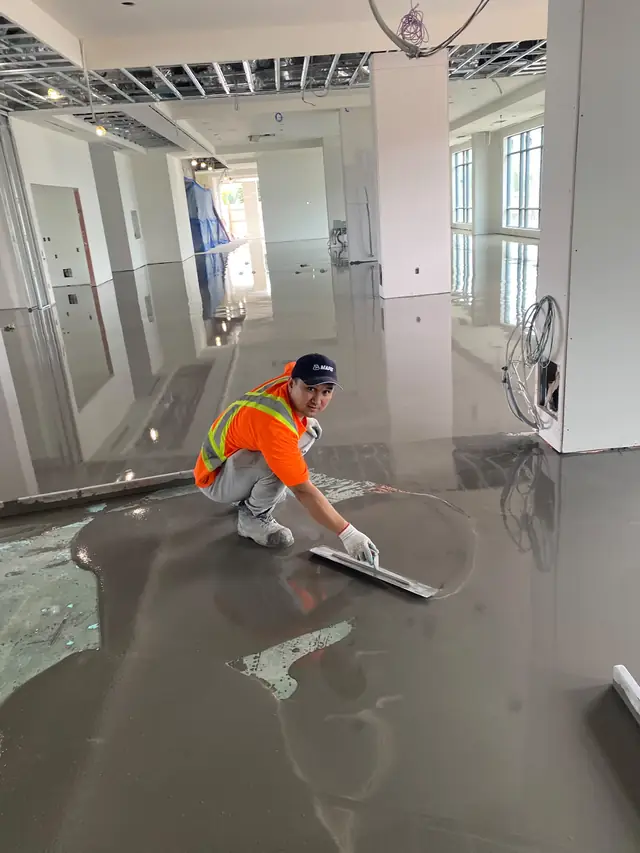 MIR crew member troweling fresh self-leveling concrete in a large commercial space