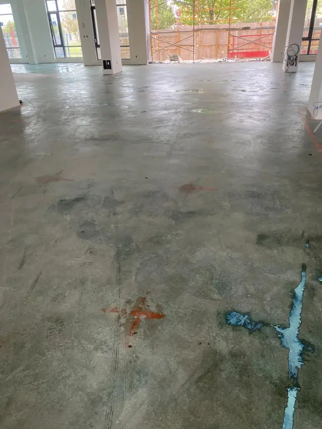 Commercial retail concrete floor with blue adhesive residue ready for grinding