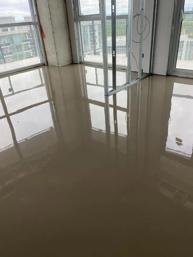 Glossy wet self-leveling concrete reflecting the window wall in a high-rise condo suite