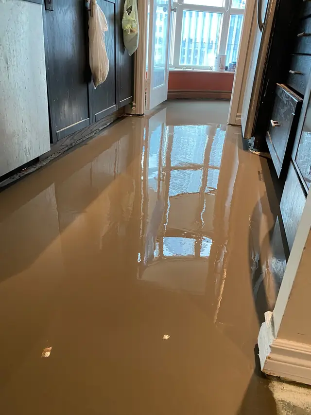 Self-leveling concrete floor in a condo kitchen next to installed cabinets and appliances