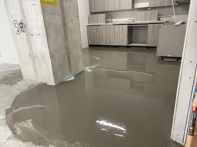 Self-leveling concrete poured around kitchen cabinets and a concrete column in a condo