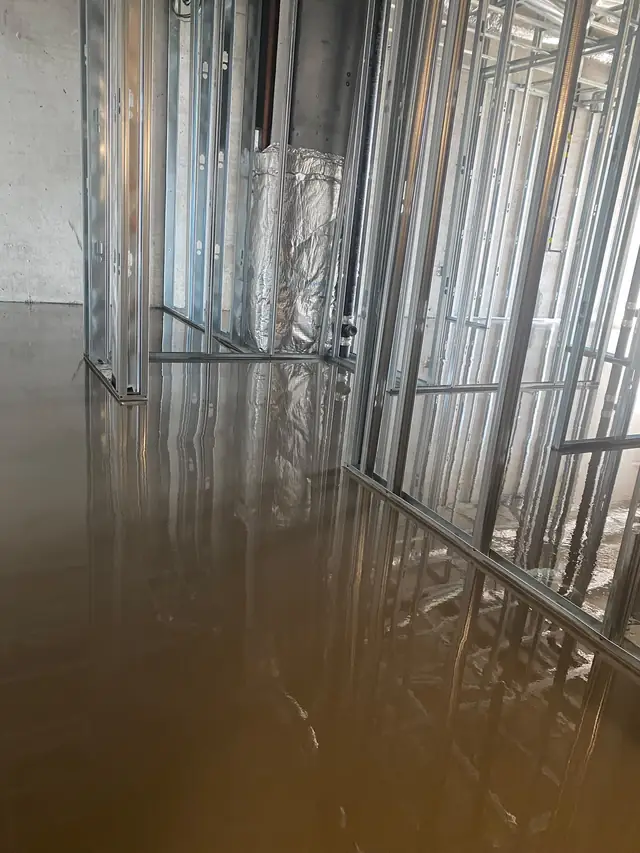 Self-leveling concrete flowing through a framed condo unit before drywall installation